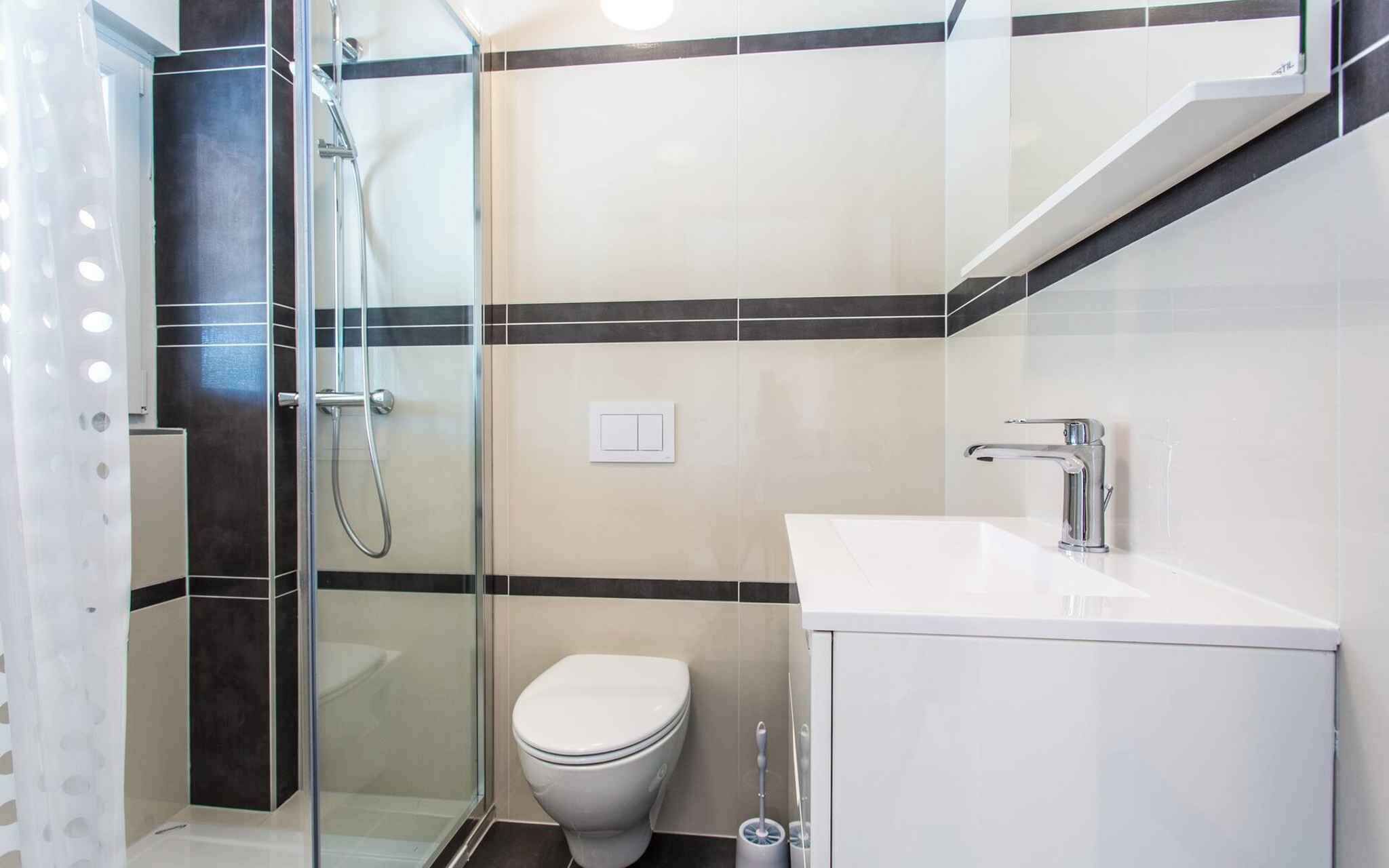 A modern bathroom with a glass-enclosed shower, a white toilet, and a white sink with a chrome faucet.