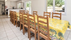 A dining area with a long table covered with a yellow tablecloth, surrounded by wooden chairs. - Lovely home in Courry with house a mountain view (Courry)