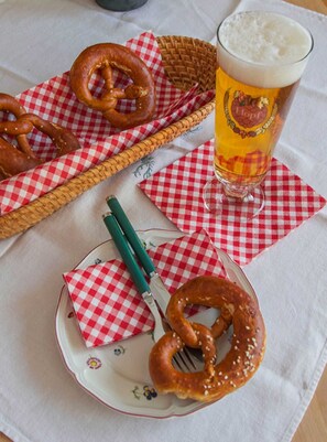 Un tavolo con bretzel, un bicchiere di birra e un coltello su un tovagliolo a quadretti.