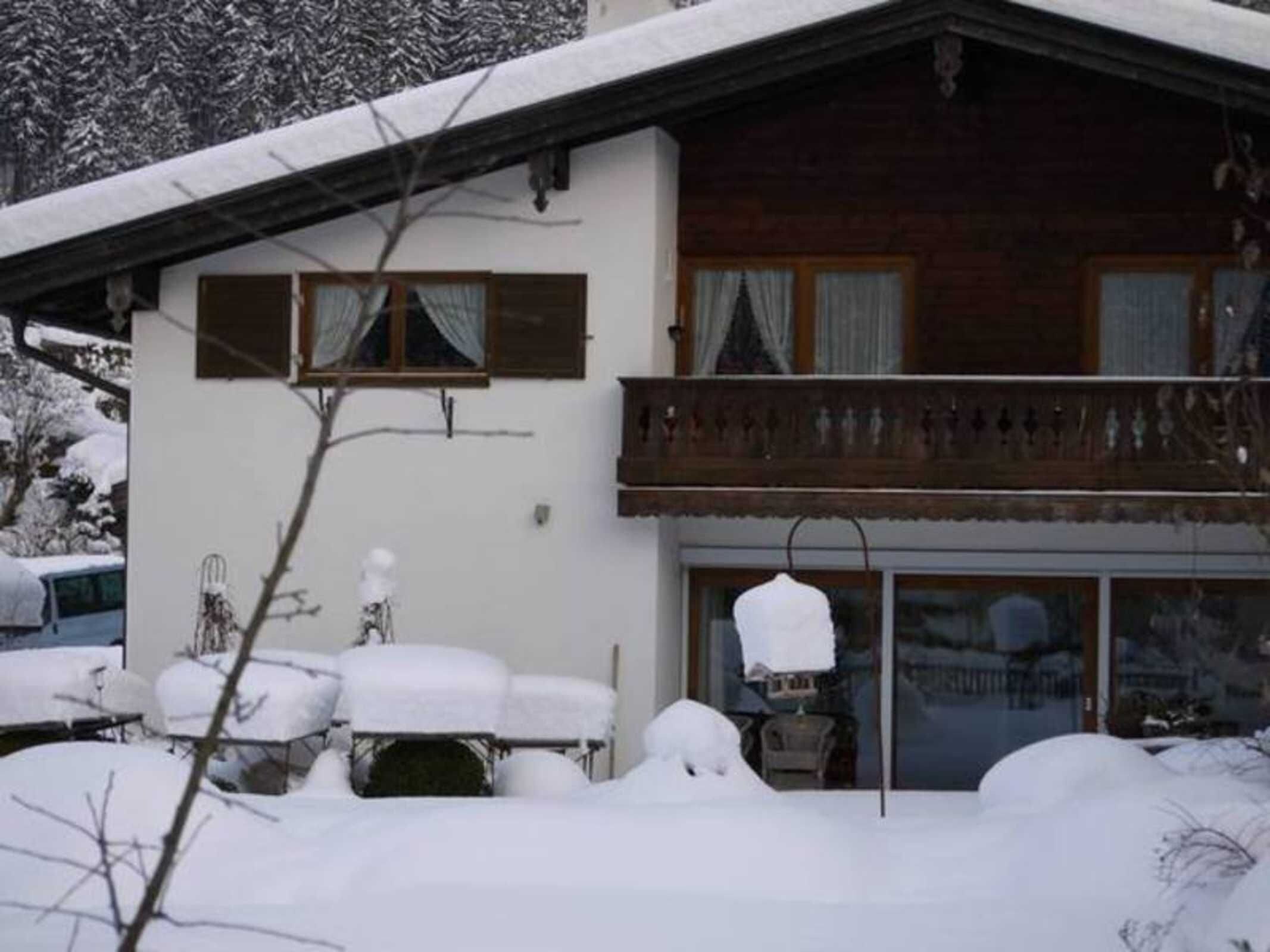A two-story building with a balcony, covered in snow.