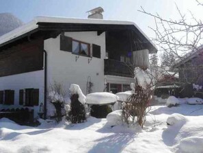 A two-story building with a sloped roof, a balcony, and a window. Snow is visible on the ground and around the building. - House Strillinger, Kreuth-Riedlern - Vacation Apartment Strillinger (Kreuth)