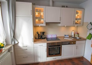 A kitchen with white cabinets, a coffee maker, a kettle, and a dish rack. - House Strillinger, Kreuth-Riedlern - Vacation Apartment Strillinger (Kreuth)