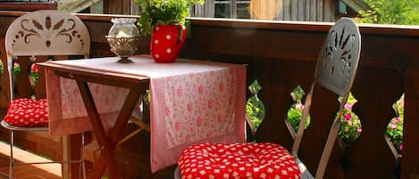 A terrace with a table and chairs, a potted plant, and a wooden fence.