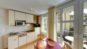 A compact kitchen with white cabinets, a microwave, and a dining area with a table and chairs.