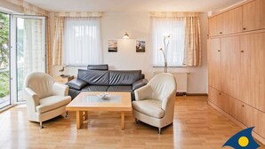 Un salon moderne comprenant un canapé, deux fauteuils, une table basse et une grande fenêtre avec des rideaux.