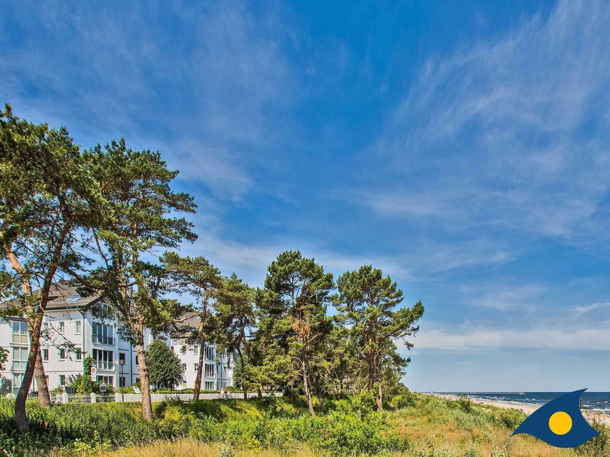 Zona residencial costera con edificios de varios pisos, abundante vegetación y una vista despejada del mar.