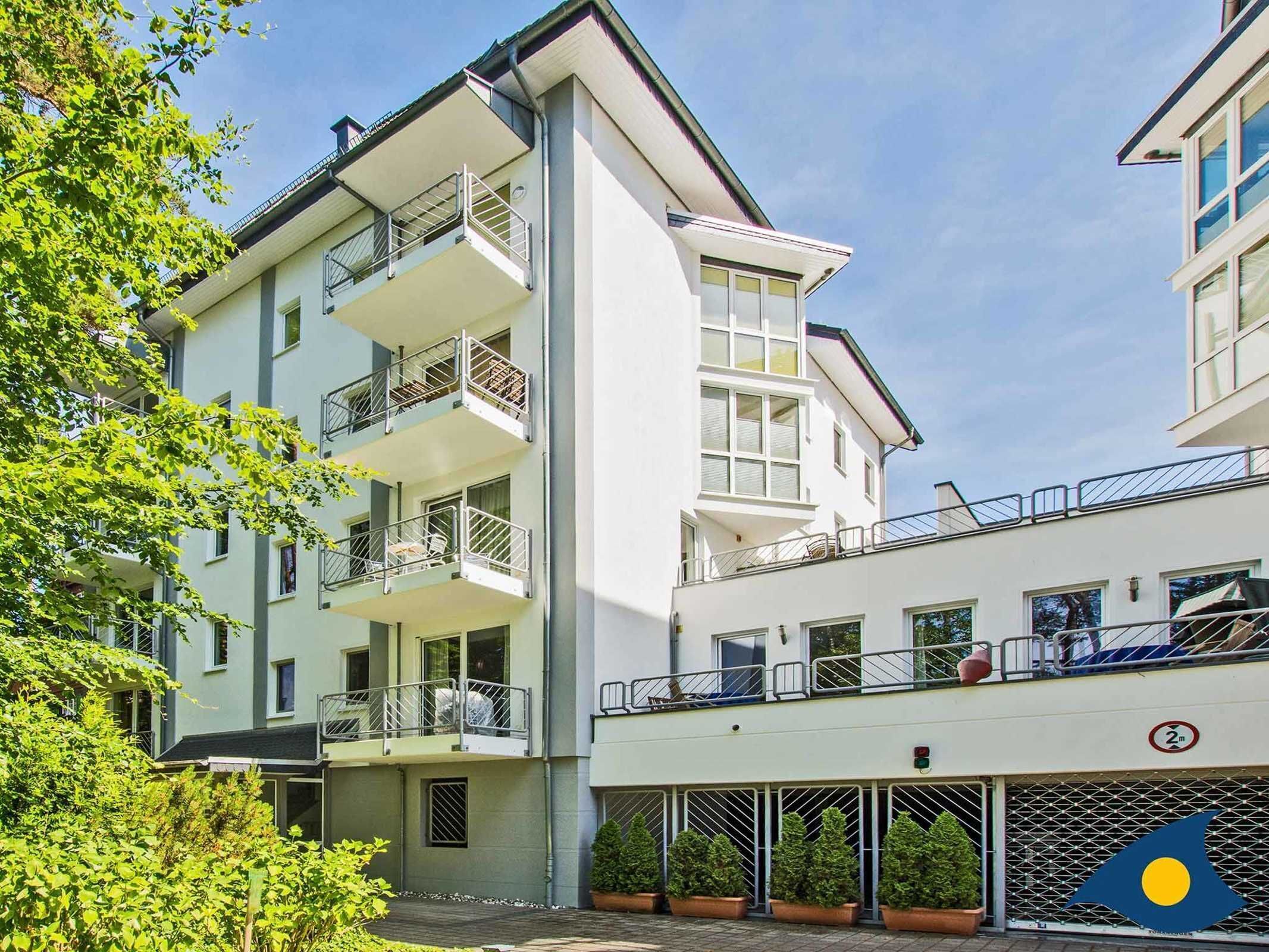 Un immeuble résidentiel à plusieurs étages, doté de balcons, d’une entrée sécurisée et surplombant un ciel dégagé.