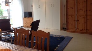 A dining area with a table, chairs, and a television on a wooden cabinet. There are cabinets and a large wooden wardrobe in the background. - Vacation apartment on Lake Mirower See (with balcony) left Whg.2 - Ferienwohnungen am See (Mirow)