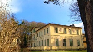 Un grand bâtiment à deux étages, doté d’une façade symétrique, de nombreuses fenêtres et d’une entrée centrale.