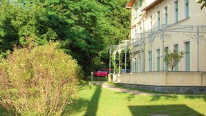 Un bâtiment à la façade symétrique, doté d’une allée couverte et d’une pelouse bien entretenue.