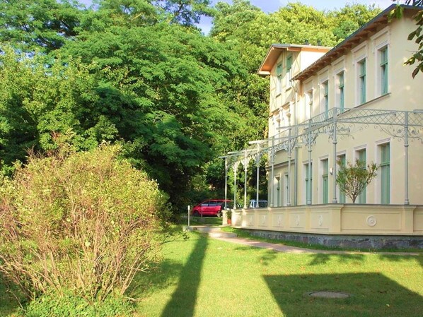A building with a symmetrical facade, a covered walkway, and a well-maintained lawn.
