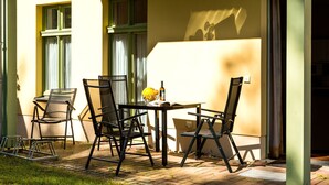 Une terrasse extérieure avec une table et des chaises, une bouteille et un vase.