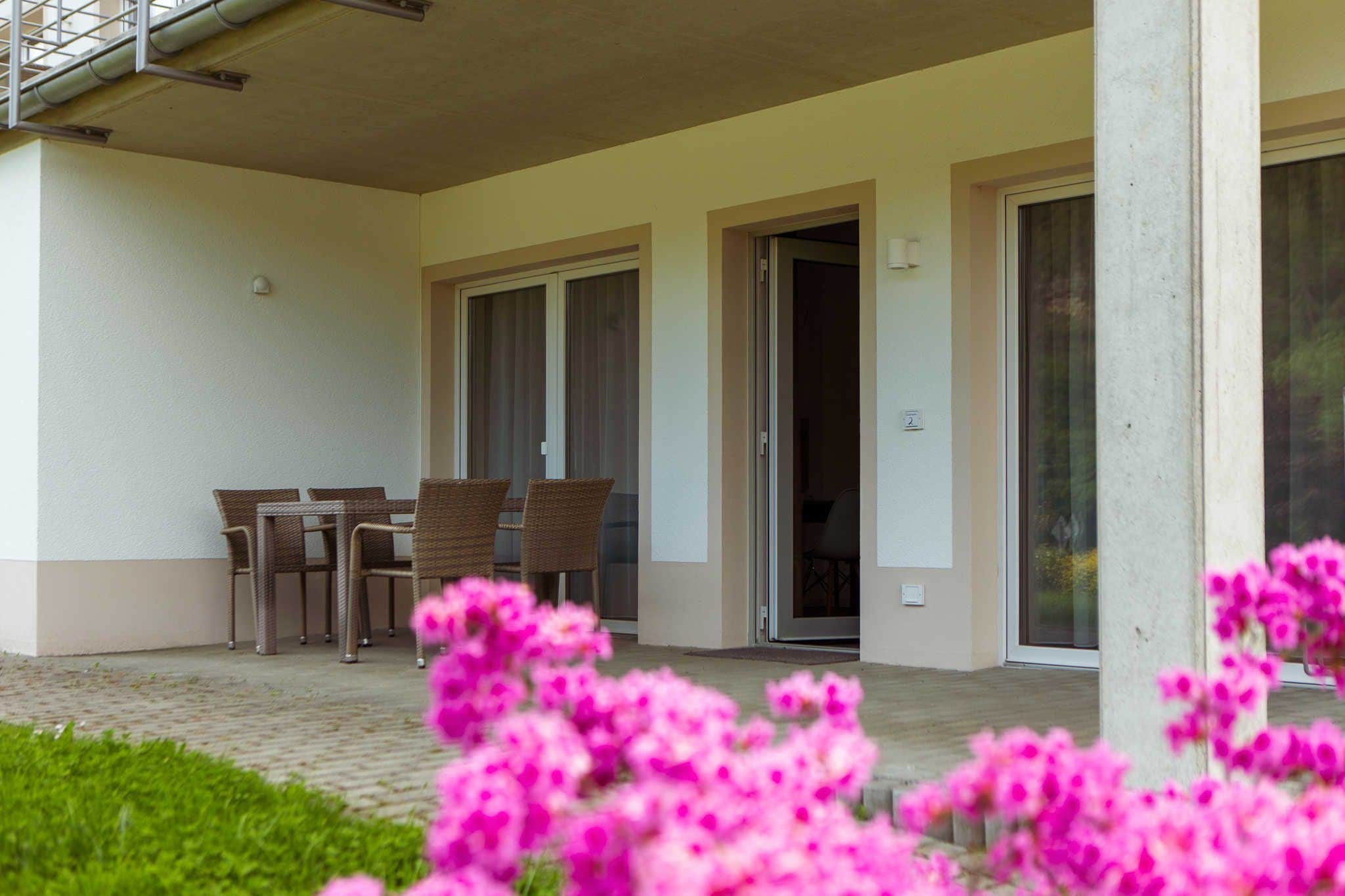 A covered outdoor area with a table and chairs, a door, and a window.