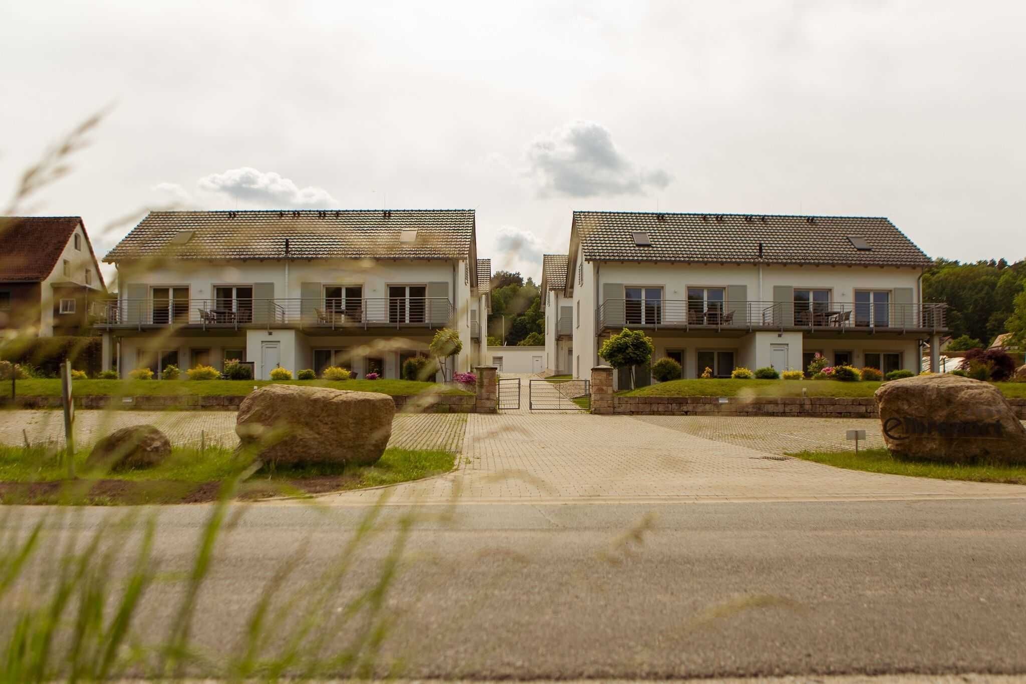 A residential building with a symmetrical facade, a gated entrance, and a driveway leading to the main entrance.
