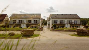 A residential building with a symmetrical facade, a gated entrance, and a driveway leading to the main entrance.