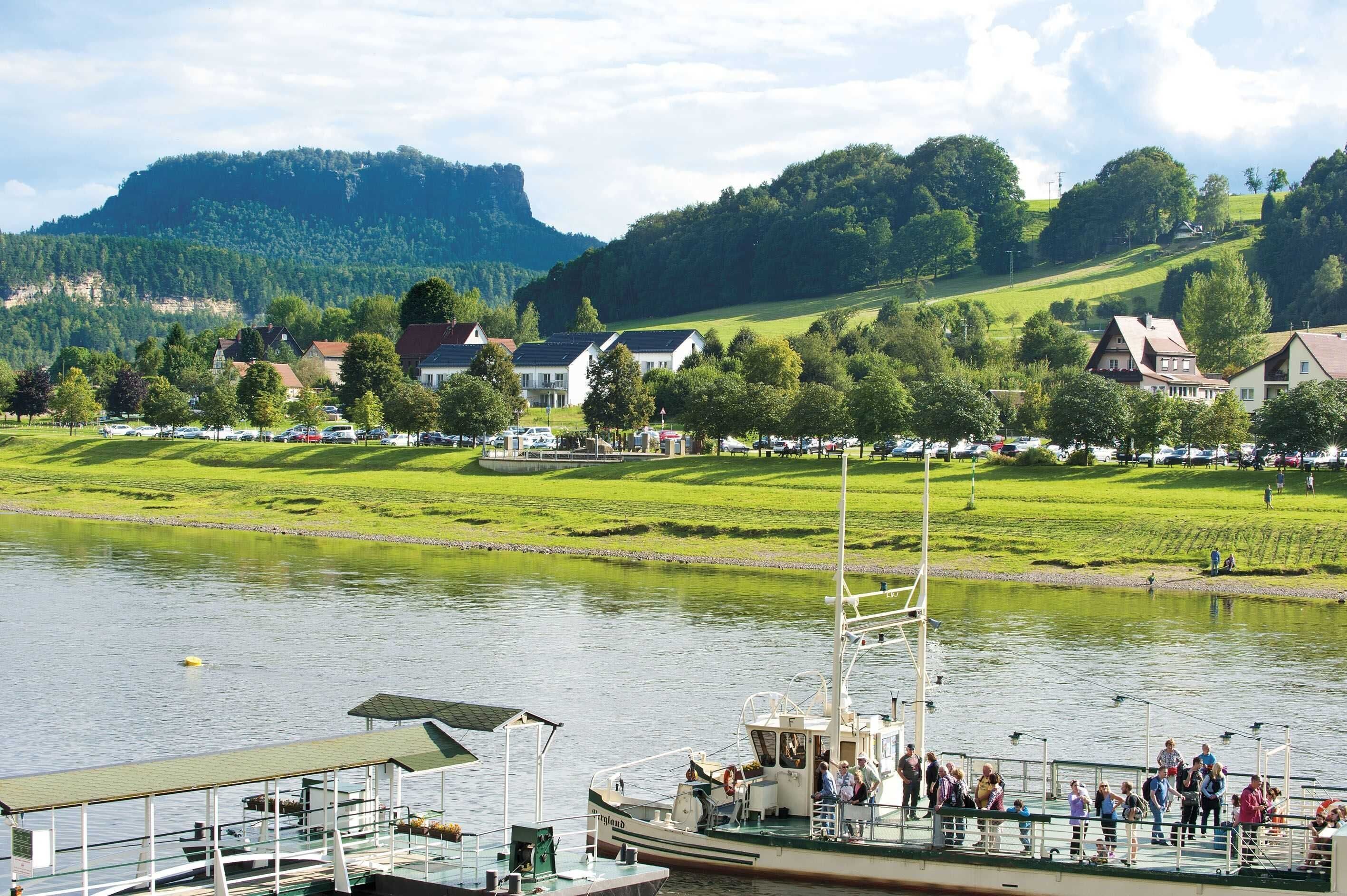 A river with a boat docked, surrounded by houses and greenery.