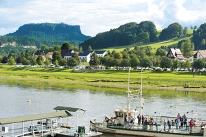 Um rio com um barco atracado, rodeado de casas e vegetação.