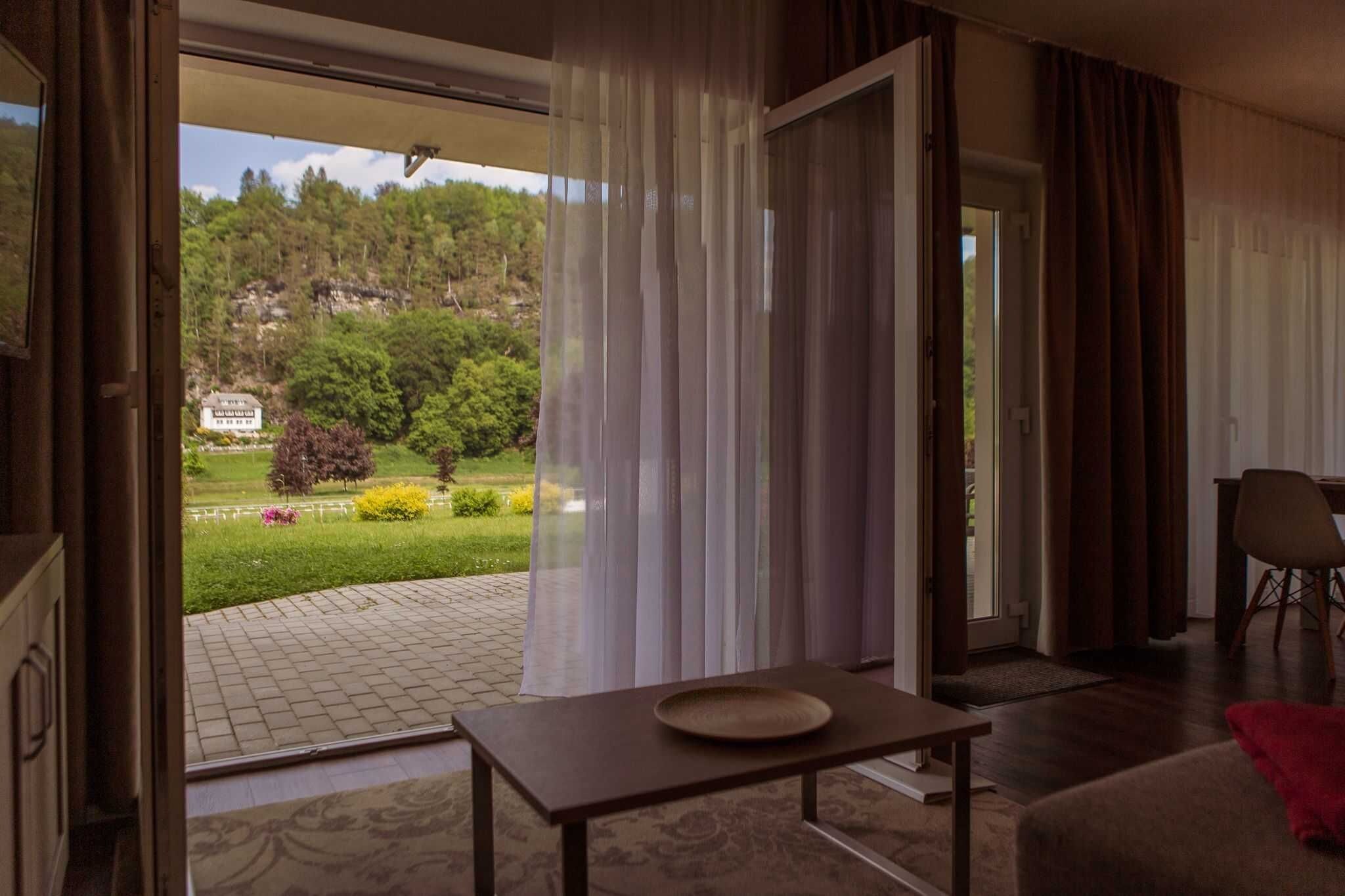 An open door leading to a garden with a sign, a table with a plate, and a chair.
