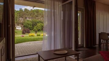An open door leading to a garden with a sign, a table with a plate, and a chair.