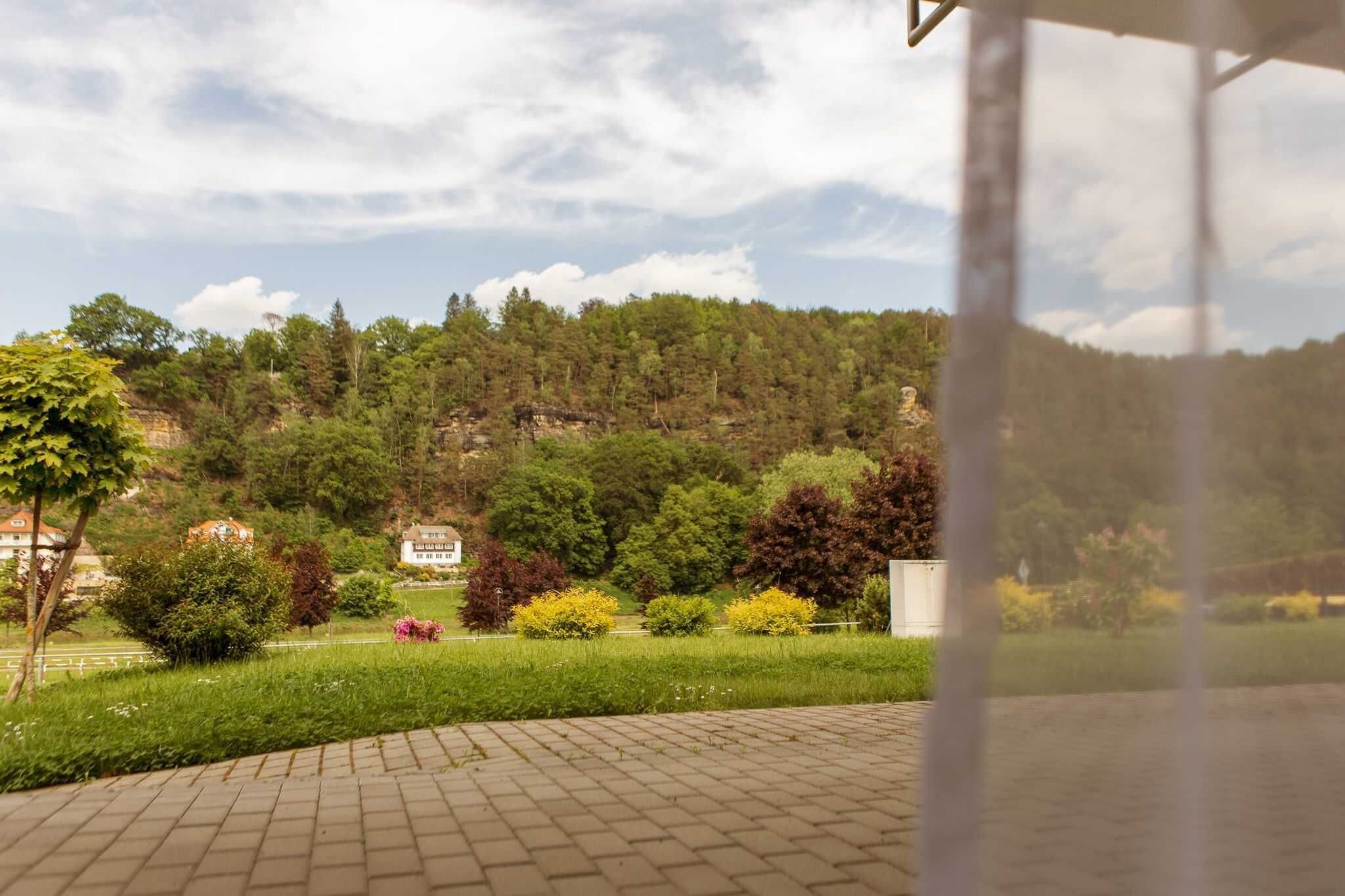 Une zone dallée offrant une vue sur un paysage verdoyant, des arbres et une colline en arrière-plan.