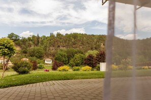 Una zona pavimentada amb vista a un paisatge verd, arbres i un turó al fons.