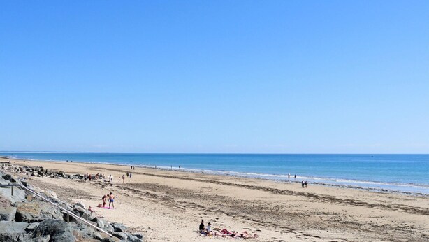 A beach with a rocky shoreline and a clear blue sky.