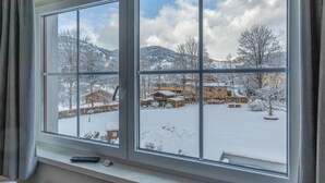 A room with a large window overlooking a snowy landscape with buildings and trees. - attraktive Ferienwohnung Wagr. (Wagrain)