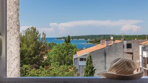 A view from a window overlooking a coastal area with buildings and trees. - Beach front apartment in Cervar Porat with WiFi (Cervar Porat)