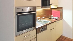 Une cuisine compacte équipée d’un four, d’un micro-ondes et d’un lave-vaisselle intégrés.