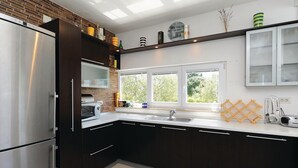 Una cocina moderna con armarios oscuros, electrodomésticos de acero inoxidable, un ventanal grande y un salpicadero de ladrillo.