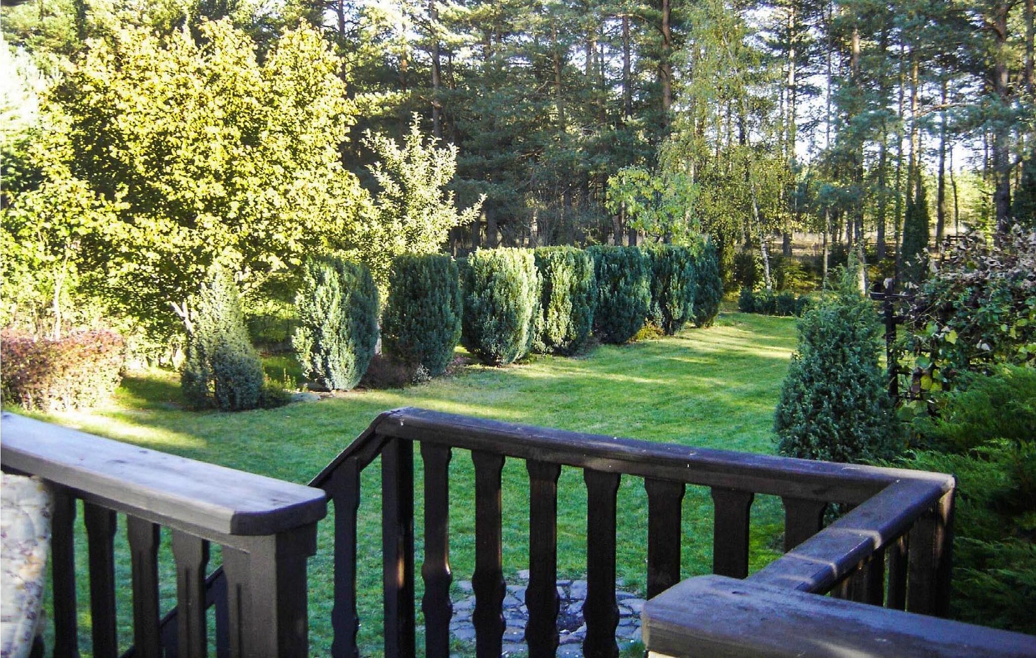 A wooden deck with a view of a well-maintained garden featuring various shrubs and trees.