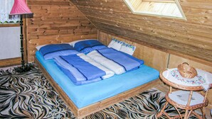 A cozy room with a bed, a lamp, a small table, and a skylight.