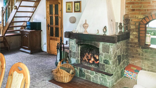 A cozy room with a stone fireplace, wooden furniture, and a staircase leading to an upper level.