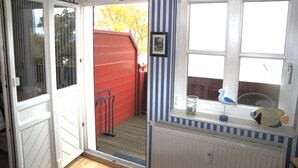 Ein Zimmer mit einer Schiebetür aus Glas, einem Fenster mit Blick auf einen roten Zaun und Bäume sowie einem Heizkörper an der Wand.