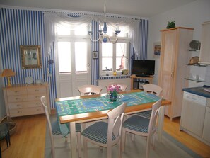 A dining area with a wooden table, chairs, a chandelier, and a television.