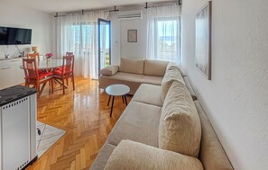 Un espace de vie comprenant un canapé, une table à manger avec des chaises, un téléviseur et un coin cuisine avec une cuisinière.