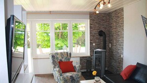 Ein gemütlicher Wohnbereich mit Kamin, einem bequemen Sessel, einer Couch und einem Fernseher.
