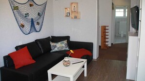 Ein Wohnzimmer mit einem schwarzen Sofa, roten Kissen, einem weißen Couchtisch und einer Wanddekoration.