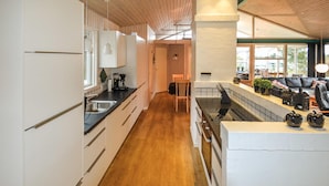 Une cuisine moderne avec des meubles en bois, un plan de travail noir et une vue sur la salle à manger.
