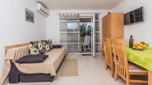 A compact living space with a sofa, a dining table, and a TV. - Holiday apartment with air conditioning and sea view (Klimno)
