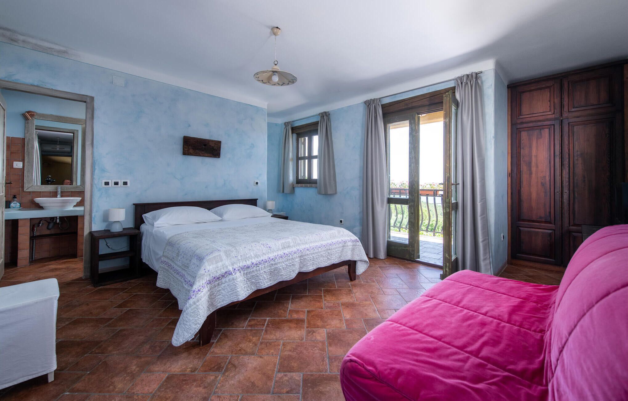 A bedroom with a bed, a nightstand, a dresser, a window, and a balcony.