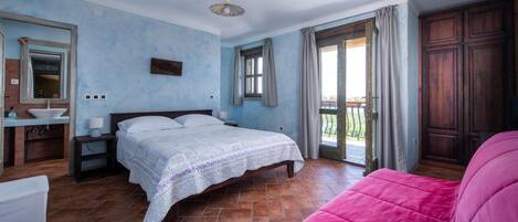 A bedroom with a bed, a nightstand, a dresser, a window, and a balcony.