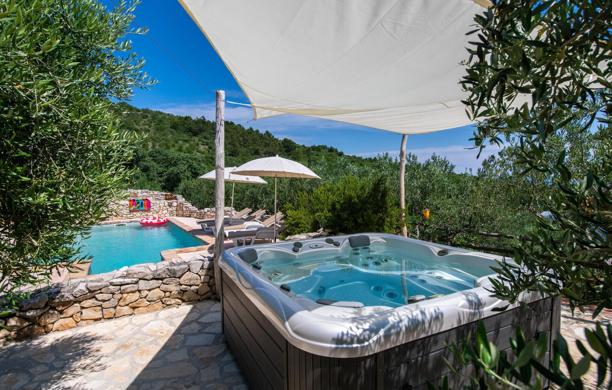 Un jacuzzi con pared de piedra y una piscina al fondo.
