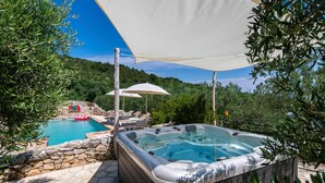 Uma banheira de hidromassagem com uma parede de pedra e uma piscina ao fundo.