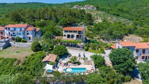 Uma propriedade em encosta com vários edifícios, piscina e vegetação exuberante.