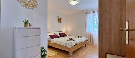 A bedroom with a bed, a dresser, a small plant, and a ceiling light.