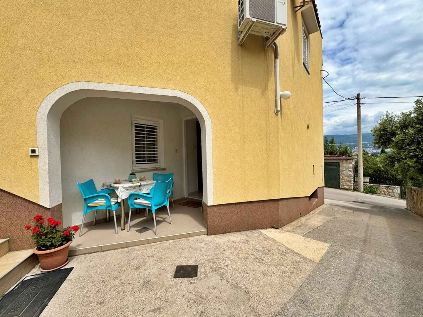 A yellow building with a covered patio area featuring a table and chairs.