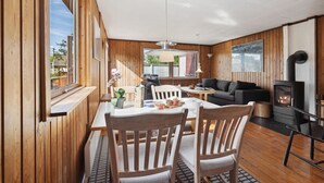A cozy cabin interior with wooden walls, a dining area with chairs and a table, a sofa, and a fireplace. - Nice home in Sydals with WiFi (Sydals)