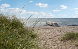 A beach with a wooden pier extending into the water, surrounded by sand and grass. - Nice home in Sydals with WiFi (Sydals)