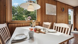 A dining area with a wooden table, chairs, a window with a view of greenery, a map on the wall, and a clock. - Nice home in Sydals with WiFi (Sydals)